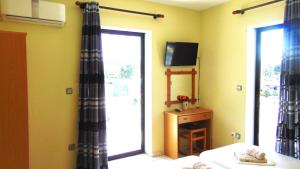 1 dormitorio con cama, ventana y TV en Central Apartments, en Paralia Dionisiou