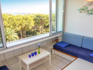 a room with a blue couch and two windows at Apartment Athéna Résidence by Interhome in Bandol