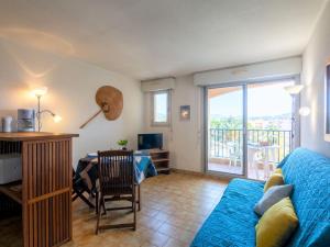 a living room with a blue couch and a table and a desk at Studio La Palmeraie II-3 by Interhome in Sainte-Maxime