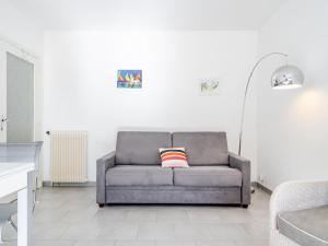 ein graues Sofa in einem Wohnzimmer mit einer weißen Wand in der Unterkunft Studio Joanis-1 by Interhome in Saint-Jean-de-Luz