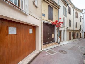 un edificio con una puerta de madera y flores rojas en Apartment Rue de la Pompe by Interhome, en Antibes