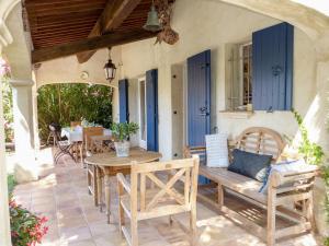 レ・ズィサンブルにあるHoliday Home Le Petit Olivier by Interhomeの青いドア、木製のテーブルと椅子付きのパティオ