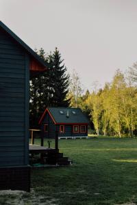 a red and black house in a grass field at Paunu Talu - Majutus ja Kajakid in Kekra