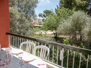 una mesa con sillas blancas en un balcón con árboles en Apartment Hameau de Provence by Interhome en Bandol