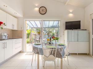 eine Küche mit einem Tisch und einer Uhr an der Wand in der Unterkunft Holiday Home Les Oliviers by Interhome in Talmont