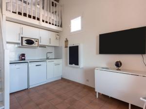 cocina con armarios blancos y TV de pantalla plana en Apartment Grand Bassin by Interhome, en Grimaud