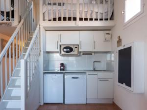 una pequeña cocina con armarios blancos y una escalera en Apartment Grand Bassin by Interhome, en Grimaud