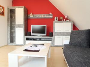 a living room with a red wall and a tv at Apartment Seestern by Interhome in Hooksiel