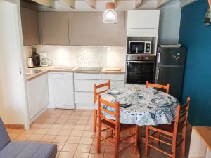 Una cocina con una mesa con sillas y un refrigerador. en Holiday Home Rivages d'Olonne by Interhome, en La Pironnière