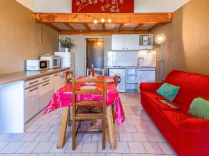 a kitchen with a table and a red couch at Apartment Port Saint Michel by Interhome in Cap d'Agde