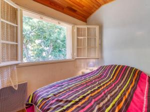 1 dormitorio con una manta colorida en una cama con ventana en Holiday Home La Côte d'Argent - MVT175 by Interhome, en Montalivet-les-Bains