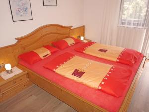 ein Schlafzimmer mit einem großen Holzbett mit roten Kissen in der Unterkunft Apartment Haslwanter by Interhome in Pians
