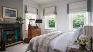 a bedroom with a bed with a fireplace and windows at Ardtara Country House in Upperlands