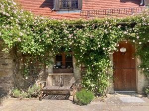 eine Holzbank vor einem Gebäude mit rosa Blumen in der Unterkunft Villa Rosencottage by Interhome in Heyda