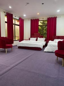 a large room with two beds and red chairs at Kamals Lodge in Skardu