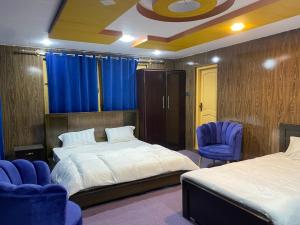 um quarto com 2 camas e 2 cadeiras azuis em Kamals Lodge em Skardu