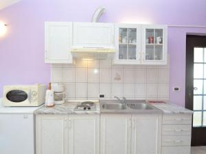 a kitchen with white cabinets and a sink and a microwave at Apartment Fabiana - PUL615 by Interhome in Valdebek