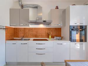 biała kuchnia z białymi szafkami i zlewem w obiekcie Apartment Villa Alba-1 by Interhome w mieście Umag