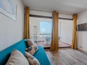 ein Wohnzimmer mit einem blauen Sofa und einem großen Fenster in der Unterkunft Apartment Martinique 2-3 by Interhome in Le Barcarès