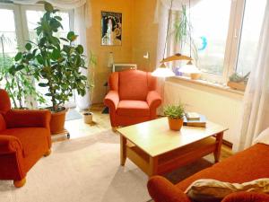 a living room with orange chairs and a coffee table at Holiday Home Natur pur am Nordseedeich by Interhome in Norddeich