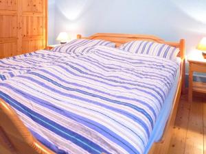 a bed with a blue and white striped blanket on it at Holiday Home Natur pur am Nordseedeich by Interhome in Norddeich +22 photos
