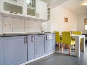 a kitchen with blue cabinets and a table with yellow chairs at Apartment Miškulin-3 by Interhome in Senj