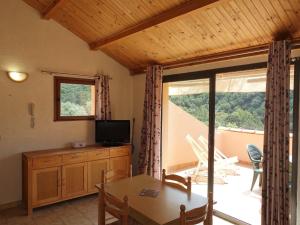 een woonkamer met een tafel, een televisie en een balkon bij Apartment Cabannaccia-1 by Interhome in Serriera