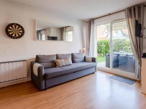 a living room with a couch and a sliding glass door at Apartment Hortensia by Interhome in Cabourg