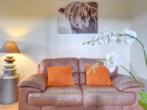 スランザイニオレンにあるHoliday Home Ffordd Fodolydd-1 by Interhomeの- リビングルーム(ブラウンレザーのソファ、オレンジの枕付)