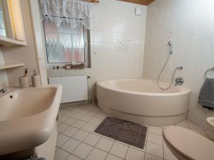 a white bathroom with a tub and a sink at Apartment Strandkorb by Interhome in Norddeich