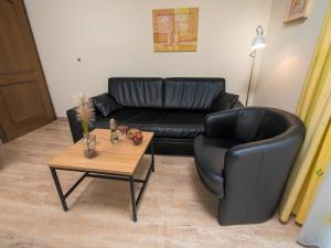 a living room with a black leather couch and a table at Apartment Strandkorb by Interhome in Norddeich