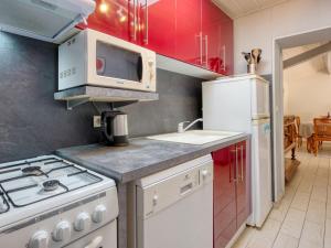La cuisine est équipée de placards rouges et d'une cuisinière blanche. dans l'établissement Holiday Home Nola - GEM100 by Interhome, à Gaillan-en-Médoc