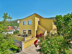 a yellow house with flowers in front of it at Apartment Miškulin-1 by Interhome in Senj