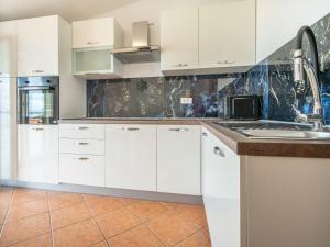 a kitchen with white cabinets and a sink at Apartment Miškulin-1 by Interhome in Senj