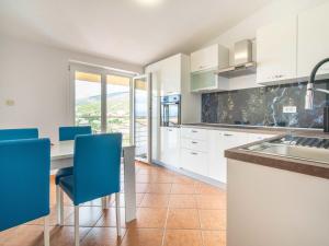 a kitchen with white cabinets and blue chairs at Apartment Miškulin-1 by Interhome in Senj