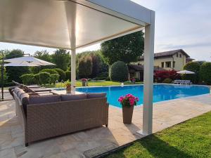 um pavilhão com cadeiras e um guarda-sol junto a uma piscina em Holiday Home Villa Carlotta by Interhome em Costigliole dʼAsti