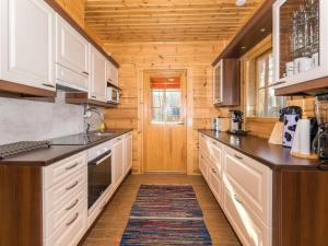 a kitchen with white cabinets and a wooden ceiling at Holiday Home Lokinsiipi by Interhome in Vähäsalmi