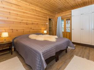 een slaapkamer met een bed in een houten kamer bij Holiday Home Lokinsiipi by Interhome in Vähäsalmi