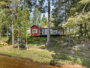 a red cabin in the woods next to a river at Chalet Löaborn - VML250 by Interhome in Kopparberg