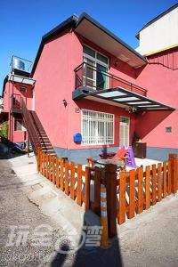 a pink house with a wooden fence in front of it at 埔里潘朵拉 in Puli