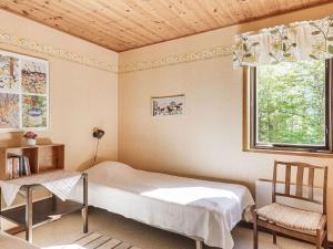 a bedroom with a bed and a chair and a window at Chalet Mjöhult Skogen - HAL022 by Interhome in Ätran