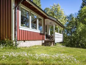 a red house with white windows and a field of flowers at Chalet Mjöhult Skogen - HAL022 by Interhome in Ätran