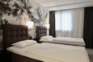 2 letti in camera d'albergo con lenzuola bianche di Super Stay Hotel, Oslo a Oslo