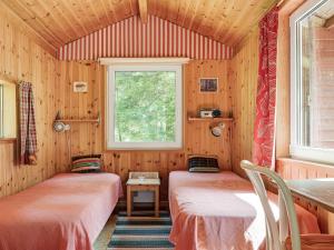 two beds in a wooden room with a window at Holiday Home Dammeberg - HAL033 by Interhome in Karl Gustav