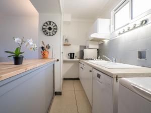 a kitchen with white cabinets and a sink and a clock at Apartment Les Mouettes by Interhome in Saint-Aygulf
