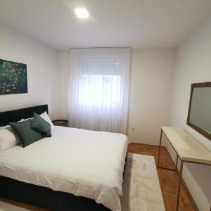 una camera con un letto bianco e una finestra di Family apartment Tuzla (100 m2) a Tuzla