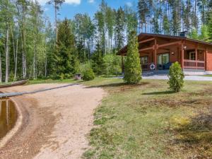 uma cabana na floresta com uma estrada de terra em frente em Holiday Home 7734 by Interhome em Kaartilankoski