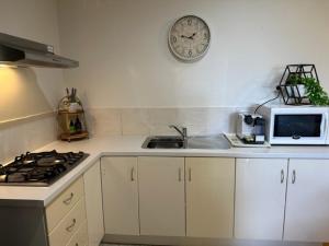 a kitchen with a clock on the wall and a microwave at Comfort Inn Getaway in Perth