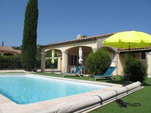 ein Pool mit gelbem Regenschirm neben einem Haus in der Unterkunft Holiday Home Allegra by Interhome in Le Val