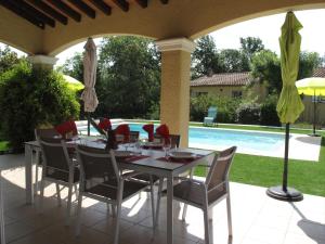 einen Tisch und Stühle auf einer Terrasse mit Pool in der Unterkunft Holiday Home Allegra by Interhome in Le Val
